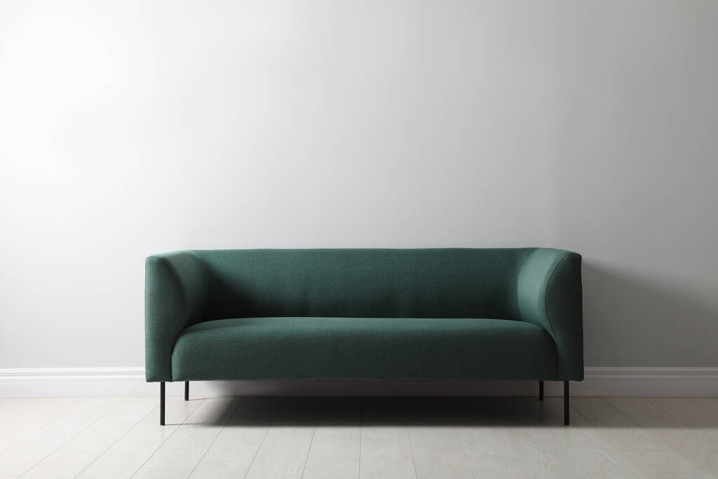 Удобный зеленый диван рядом с белой стеной внутри. Дизайн интерьера - Фото, изображение