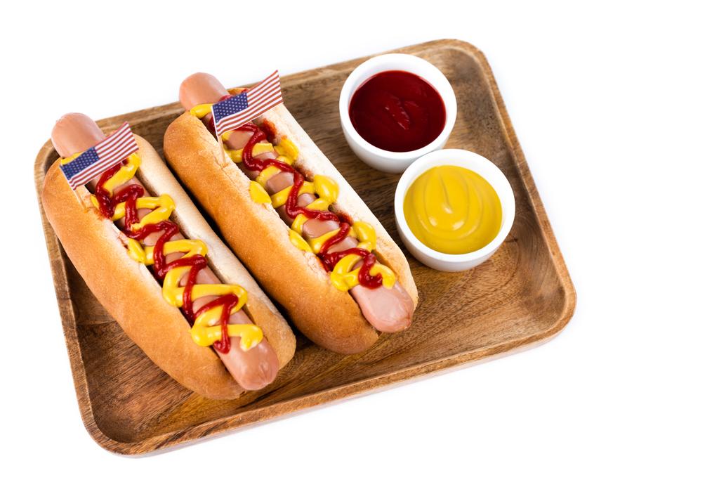 wooden tray with hot dogs and bowls with ketchup and mustard isolated on white - Photo, Image