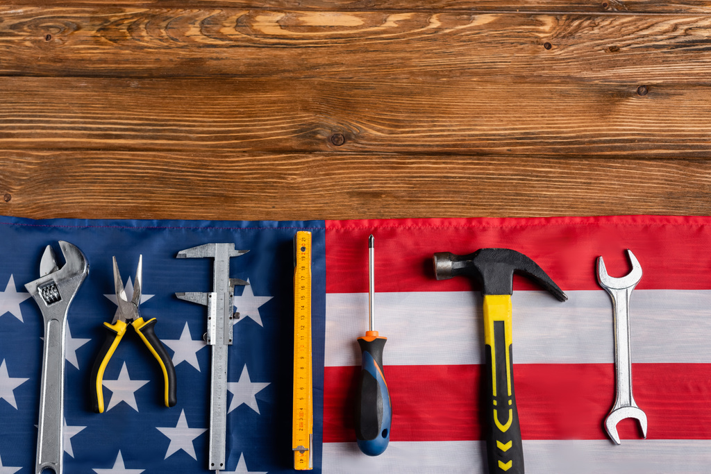 pohled shora na různé nástroje a vlajku USA na dřevěném stole, koncept pracovního dne - Fotografie, Obrázek