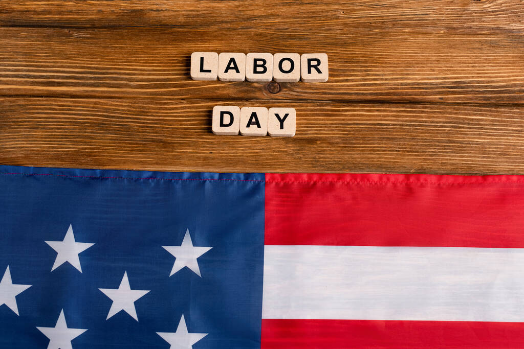 верхний вид флага США рядом с кубиками с надписью Дня труда на деревянном столе - Фото, изображение