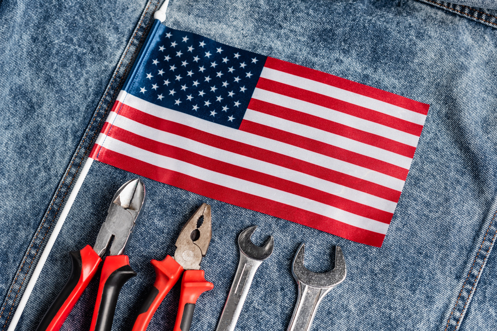 vrchní pohled na malou americkou vlajku na modré džínové látce v blízkosti různých nástrojů, koncept pracovního dne - Fotografie, Obrázek