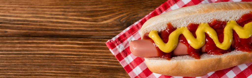 felső kilátás ízletes hot dog mártással kockás szalvéta és fa asztal, banner - Fotó, kép