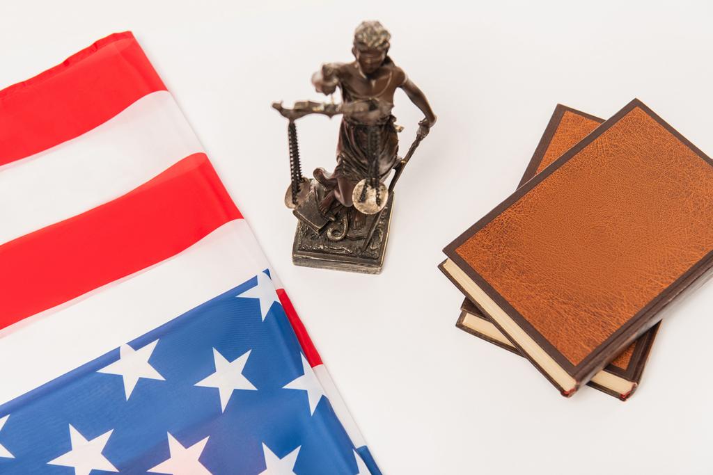 vysoký úhel pohledu na sošku spravedlnosti v blízkosti knih a americké vlajky izolované na bílém - Fotografie, Obrázek