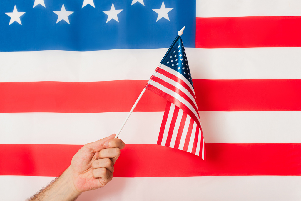 vue recadrée de l'homme patriotique tenant drapeau de l'Amérique contre symbole américain - Photo, image