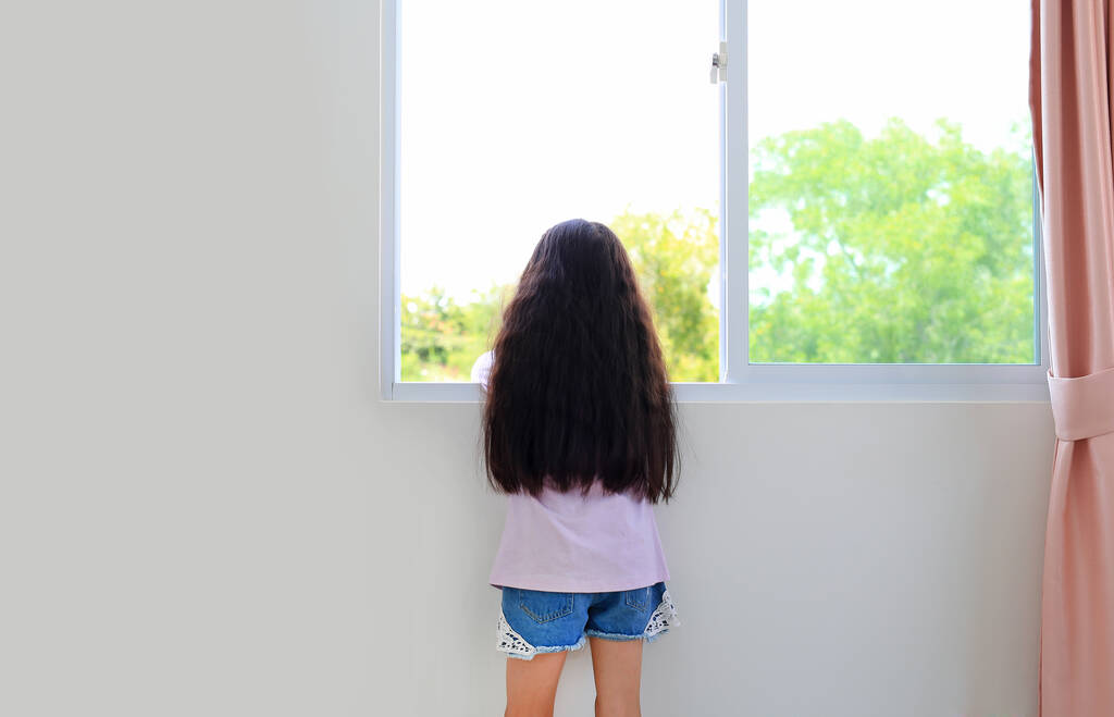 Kafkasyalı küçük kız evde, pencerenin önünde uzanıyor ve izliyor.. - Fotoğraf, Görsel