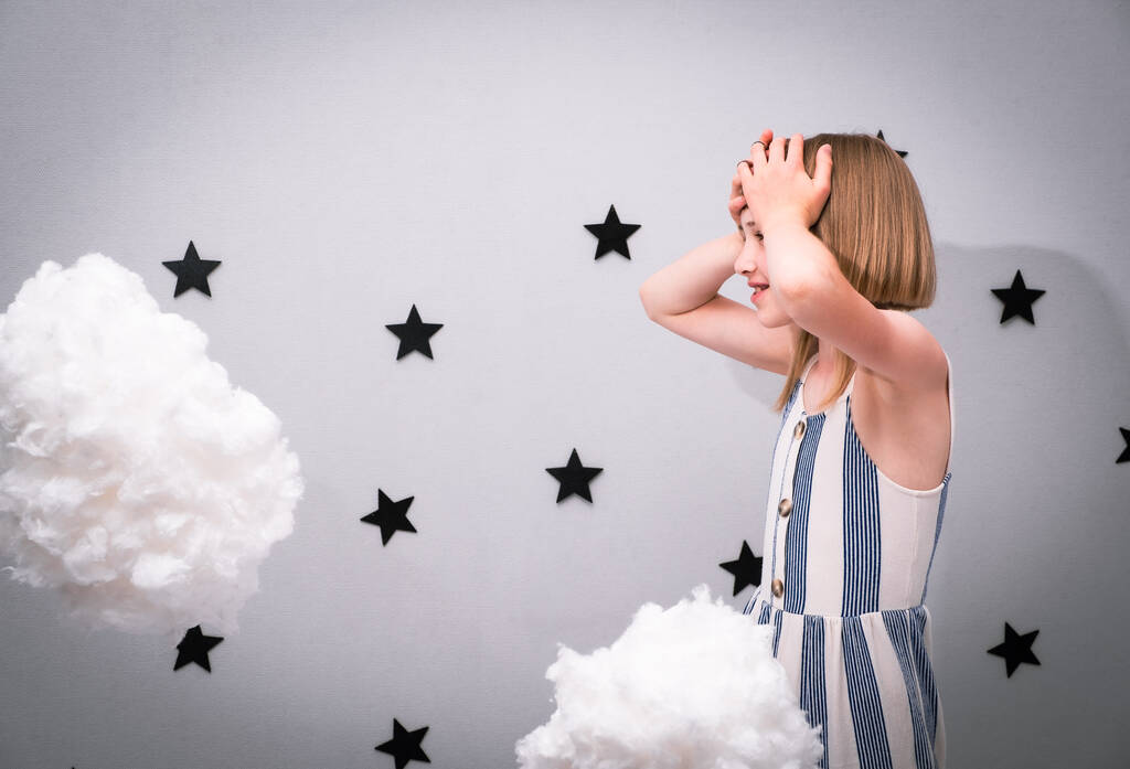 Chica adolescente sobre un fondo caprichoso: nubes y estrellas negras - Foto, imagen