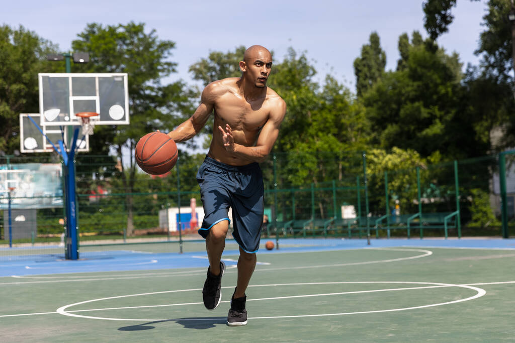 Güçlü kaslı Afro-Amerikan erkek basketbolcu sokak stadında, spor salonunda ya da dışarıda antrenman yapıyor. Yaz sporu oyunları. - Fotoğraf, Görsel