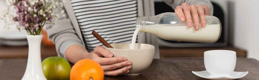 частичный вид женщины, наливающей молоко в миску, баннер - Фото, изображение