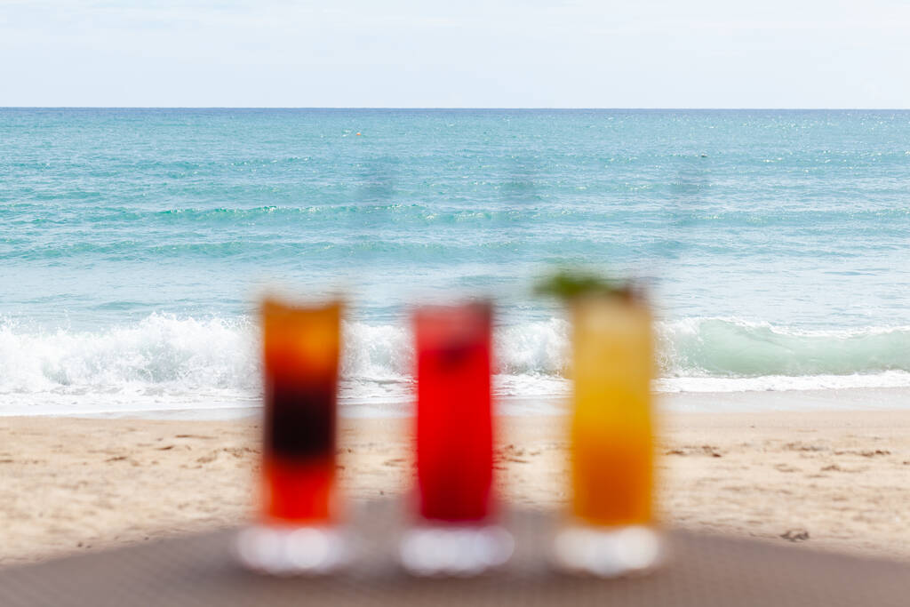 Sonsuz Deniz Ufku ile Sahildeki Masada Meyve Kokteyllerinin Odaklanmamış Seti - Fotoğraf, Görsel
