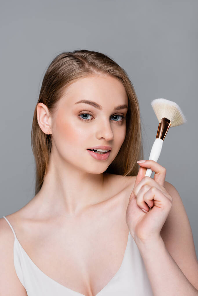 happy young woman holding cosmetic brush isolated on grey - Photo, Image