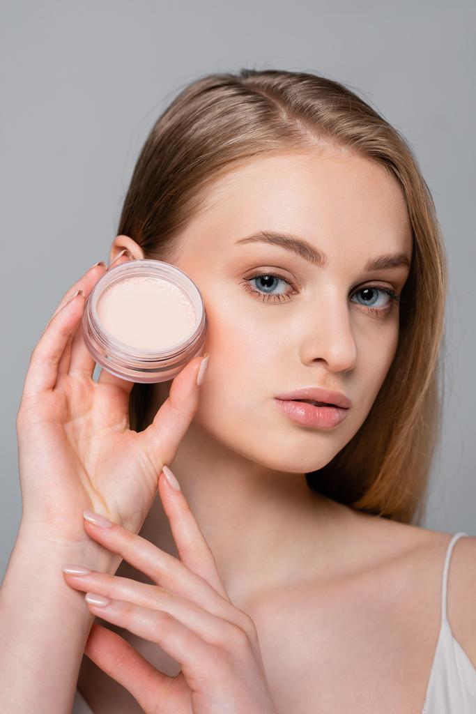 young woman holding container with face powder isolated on grey - Photo, Image