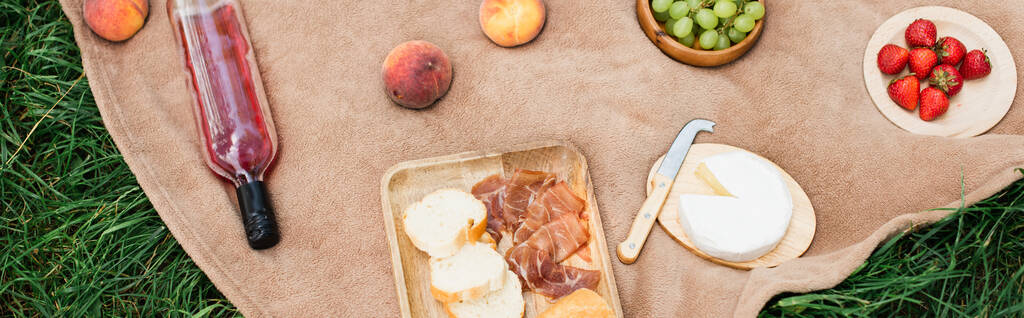 Blick von oben auf köstlichen Käse, Wein und Früchte auf Picknickdecke, Banner  - Foto, Bild