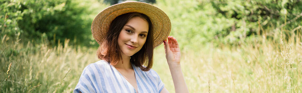 Usmívající se žena ve slunečním klobouku při pohledu na kameru v parku, banner  - Fotografie, Obrázek