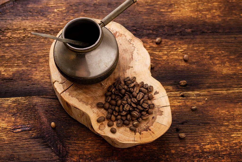 Κόκκοι καφέ και cezve σε ξύλινο φόντο. - Φωτογραφία, εικόνα