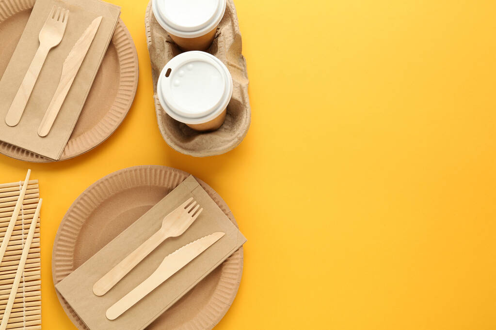 Flat lay of paper and wooden tableware on yellow background, space for text. Eco friendly lifestyle - Photo, Image