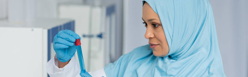 Lateks eldivenli Arap bilim adamı laboratuarda test tüpü tutuyor.  - Fotoğraf, Görsel