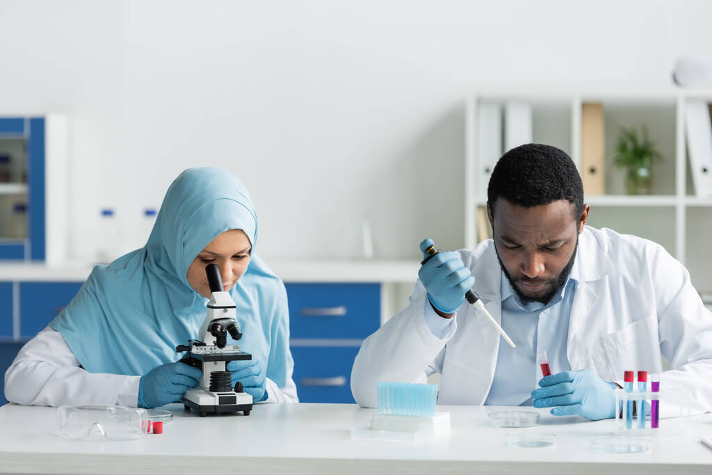 Muslimische und afrikanisch-amerikanische Wissenschaftler untersuchen Proben im Reagenzglas unter dem Mikroskop  - Foto, Bild