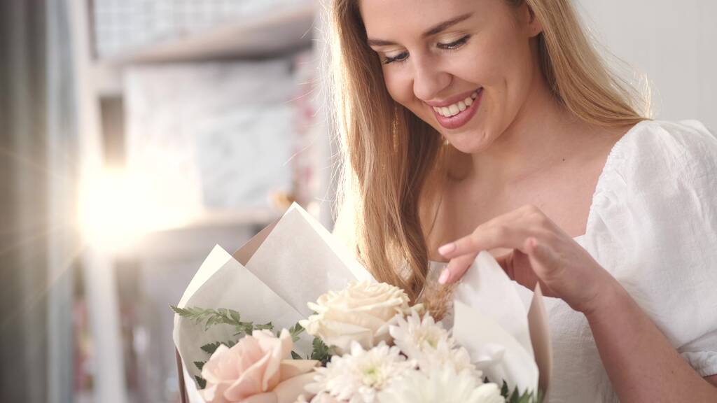 Молодая женщина ценит аромат цветочного букета - Фото, изображение