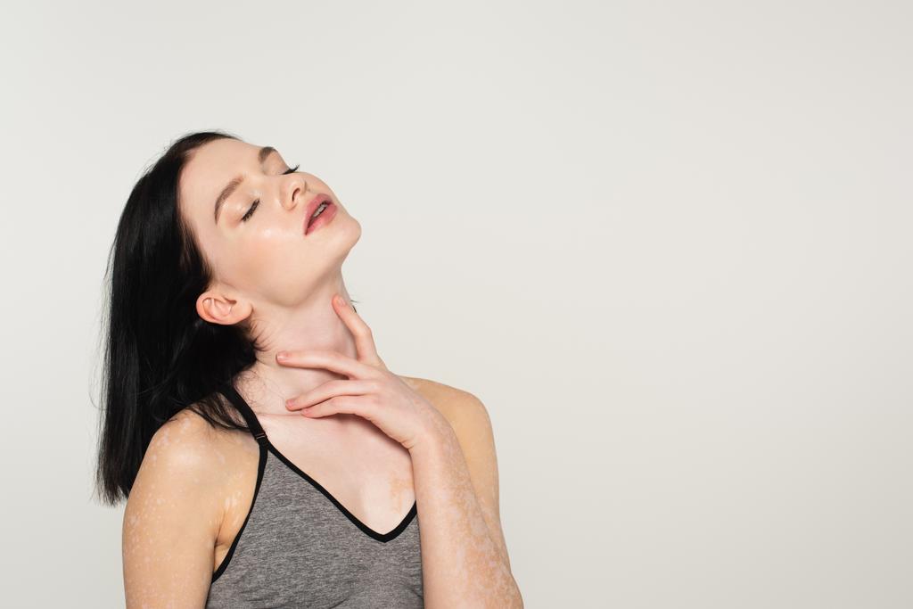 Sportnő vitiligóval és csukott szemmel, szürke nyakkal  - Fotó, kép