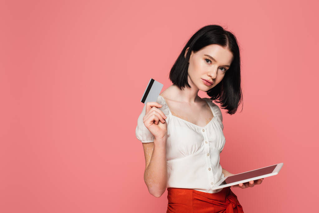 Woman with vitiligo holding digital tablet and credit card isolated on pink  - Photo, Image