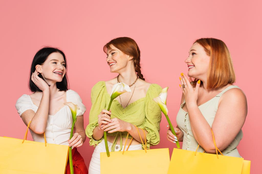 Amici positivi corpo guardando donna con vitiligine e shopping bag con fiore isolato su rosa  - Foto, immagini