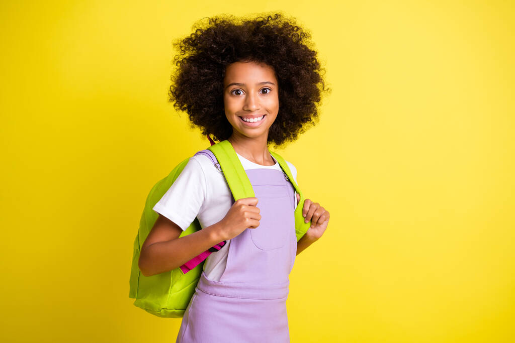 Fotografie optimistické roztomilé kudrnaté dívka nosit batoh tričko izolované na žlutém pozadí barvy - Fotografie, Obrázek