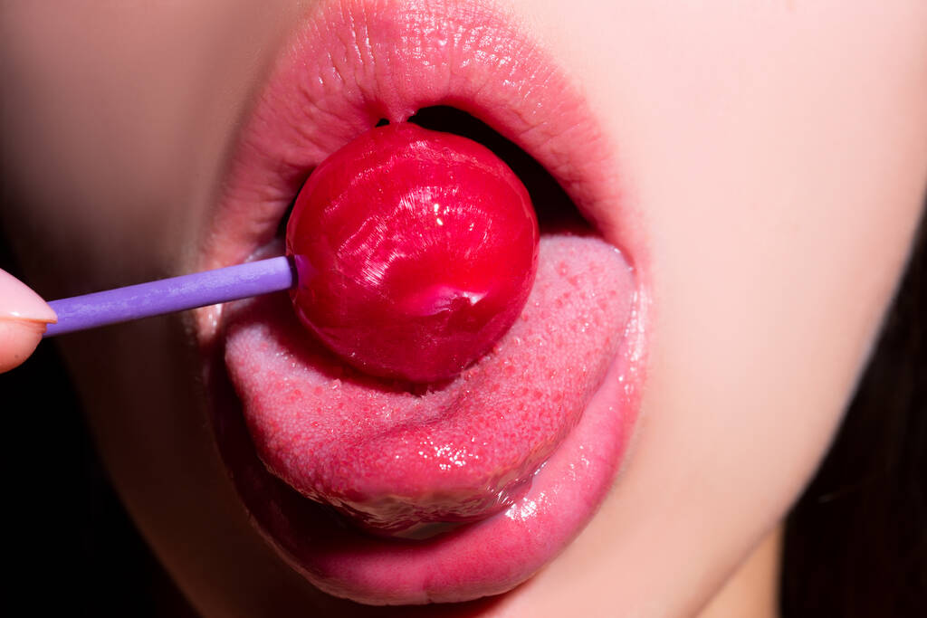セクシーな口の中でカップを食べている女の子が閉じます.女性の唇はロリポップ吸います.口の中でロリポップを保持する女性を閉じます。赤い唇、官能的でセックスショップのコンセプト. - 写真・画像