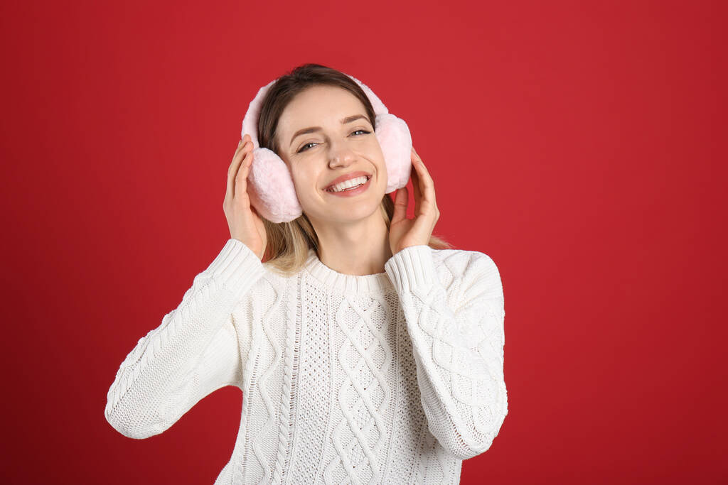 Boldog nő visel meleg fülvédőt piros háttér - Fotó, kép
