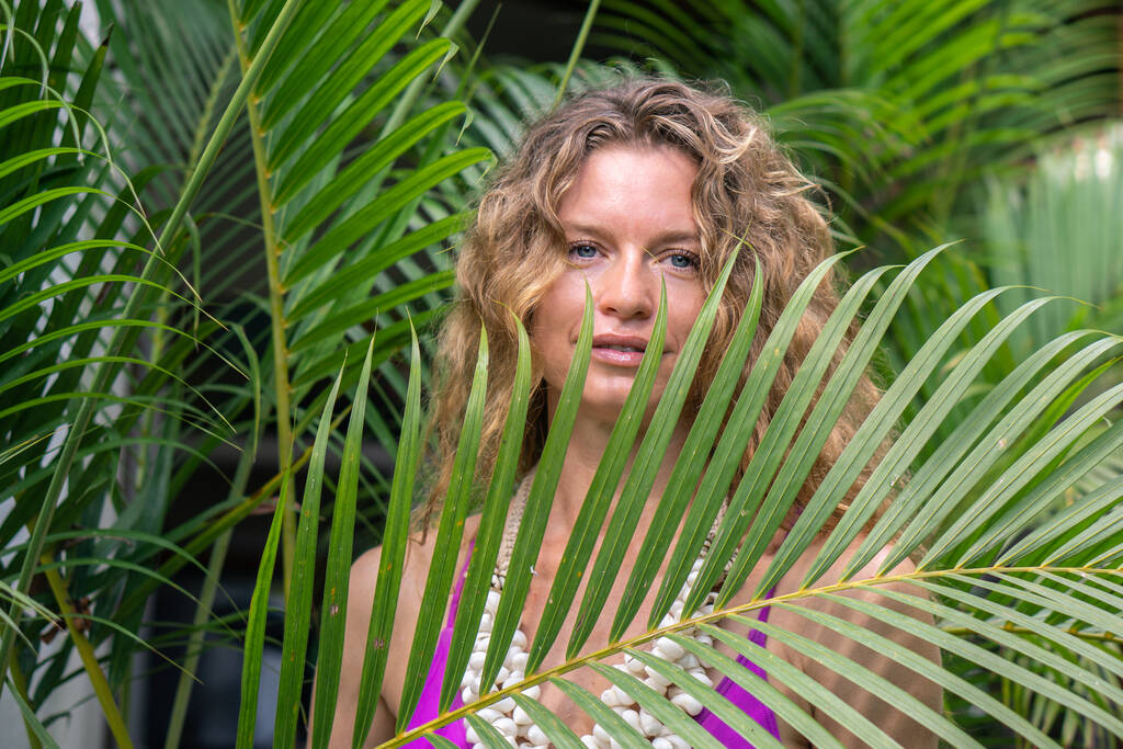 Νεαρή γυναίκα με σγουρά μακριά ξανθά μαλλιά σε τροπική πράσινη ζούγκλα με φοίνικες στο Μπαλί - Φωτογραφία, εικόνα