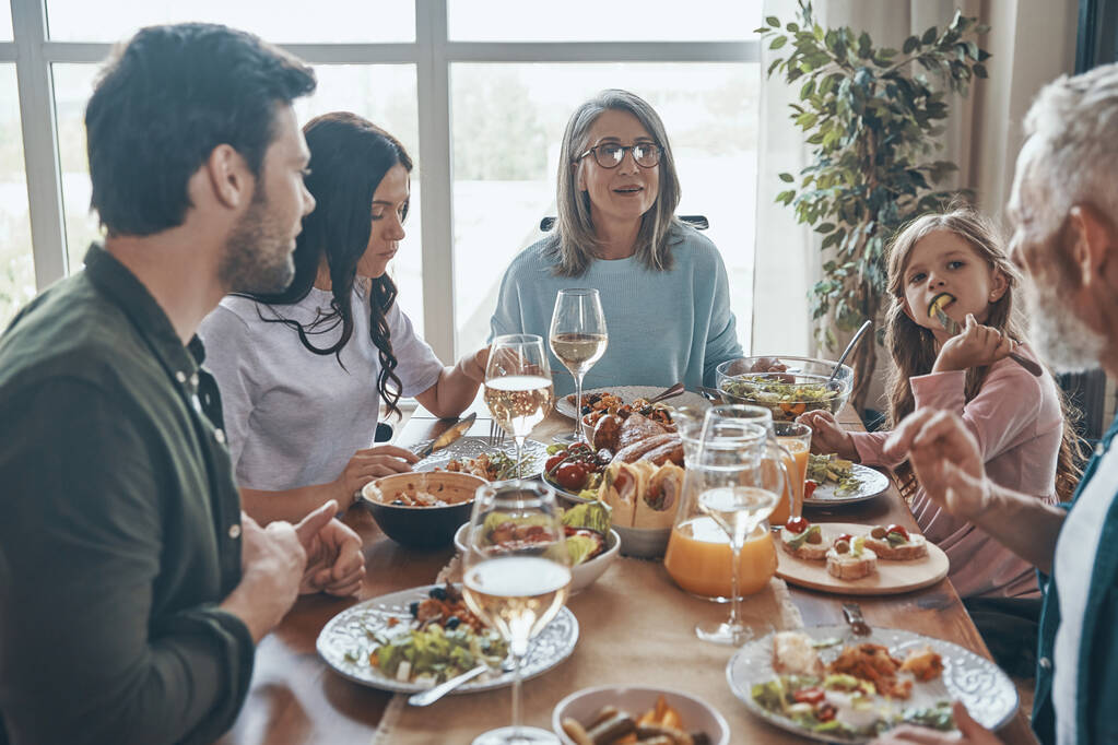 Hermosa familia multi-generación comunicándose y sonriendo mientras cenan juntos - Foto, imagen