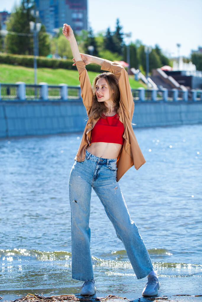 Портрет молодої стильної дівчини в бежевій блузці з довгими рукавами і блакитними джинсами
 - Фото, зображення