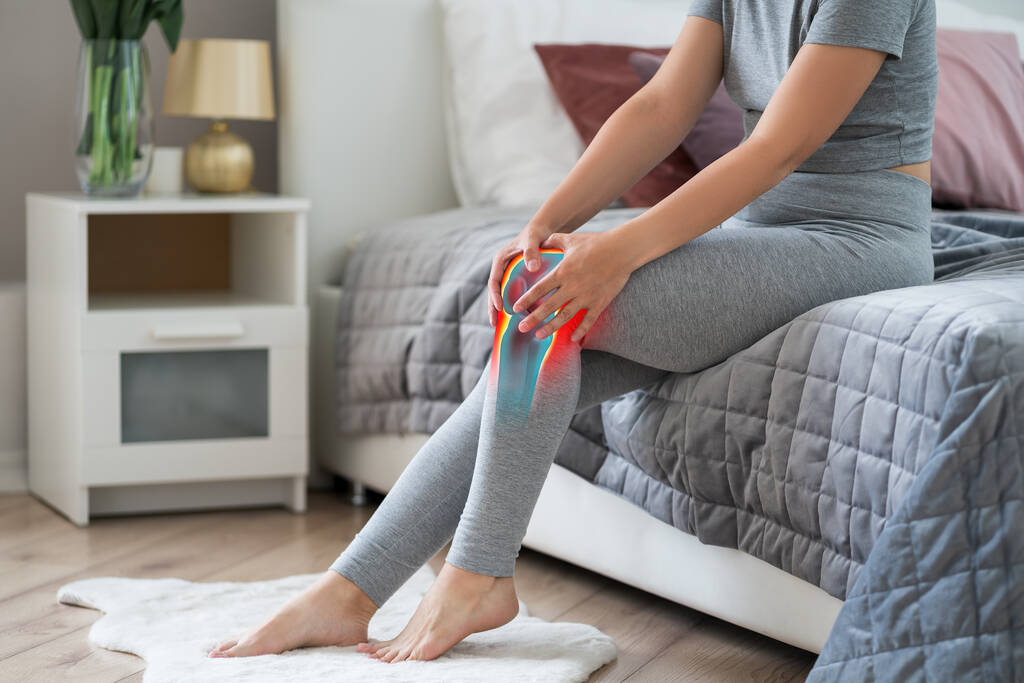 Knieschmerzen, Frau mit Arthrose und Beinschmerzen, chiropraktisches Behandlungskonzept im häuslichen Bereich, Schmerzbereich rot hervorgehoben - Foto, Bild