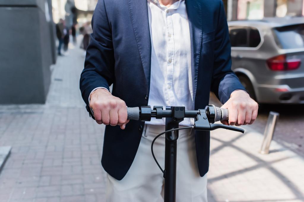 cropped view of mature businessman in blazer riding electric scooter  - Fotografie, Obrázek