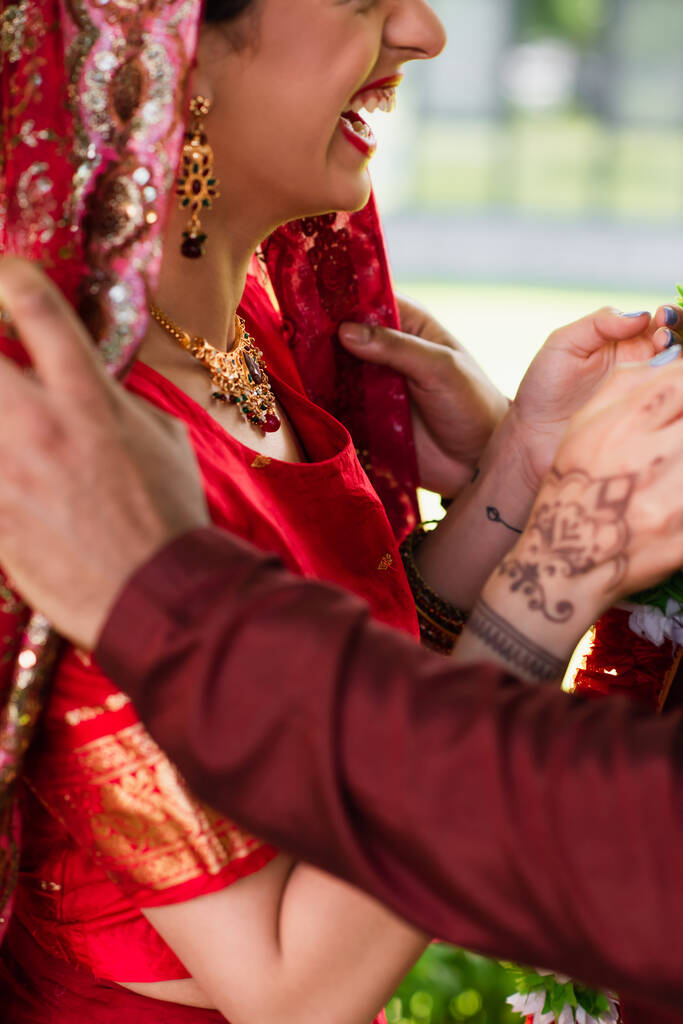 vista ritagliata di allegra sposa indiana ridere vicino allo sposo  - Foto, immagini