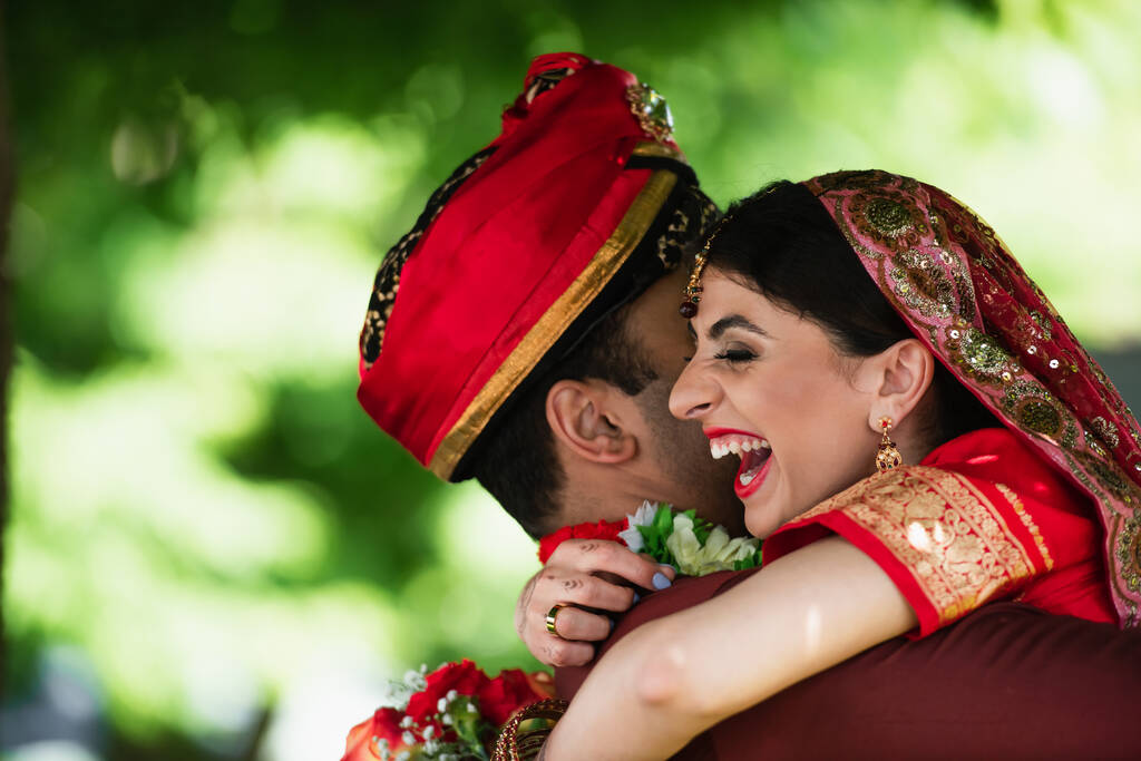 Hombre indio con turbante abrazando a la novia feliz en el pañuelo tradicional  - Foto, imagen