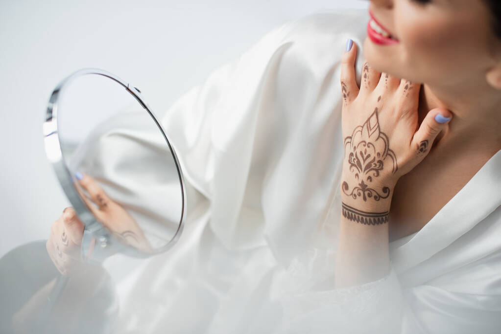 vista parcial de la novia india borrosa y feliz mirando el espejo aislado en blanco - Foto, Imagen