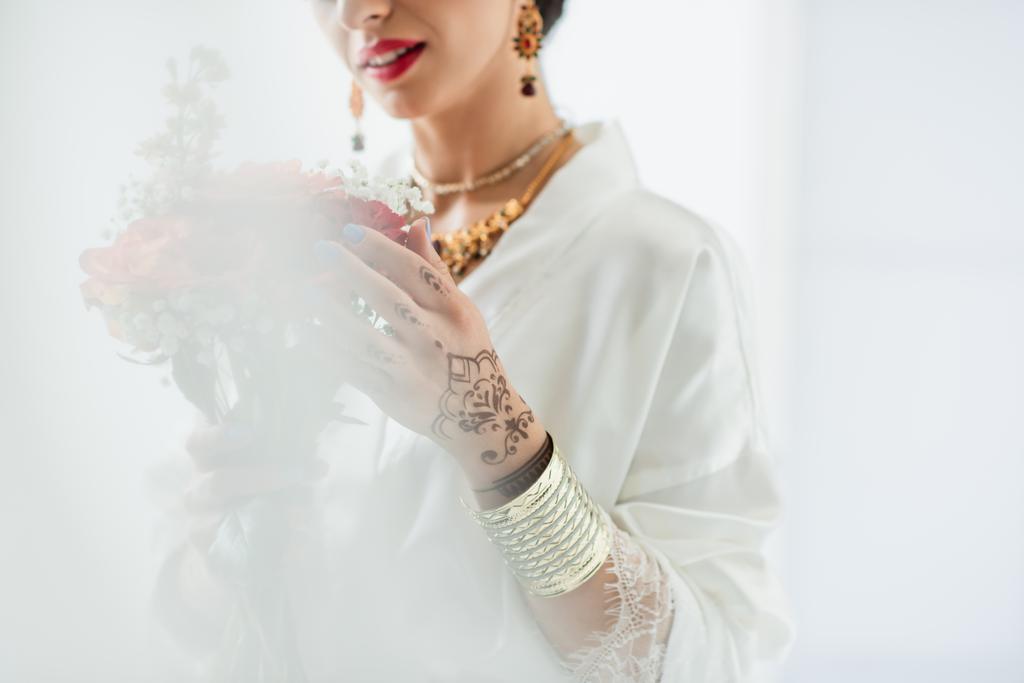 abgeschnittene Ansicht der indischen Braut mit Blumenstrauß auf weißem Grund - Foto, Bild