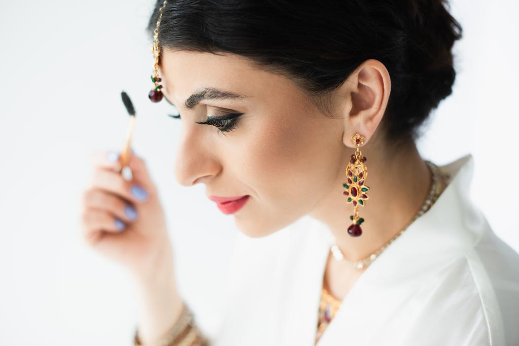 indische Braut Styling Augenbraue mit Kosmetikpinsel auf weiß  - Foto, Bild