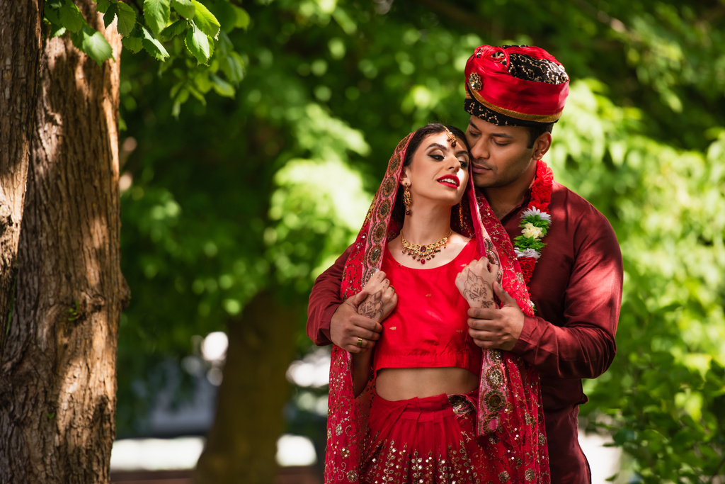 Індійський чоловік у тюрбані, який дивиться на наречену з мегнді в сарі та хустку.  - Фото, зображення