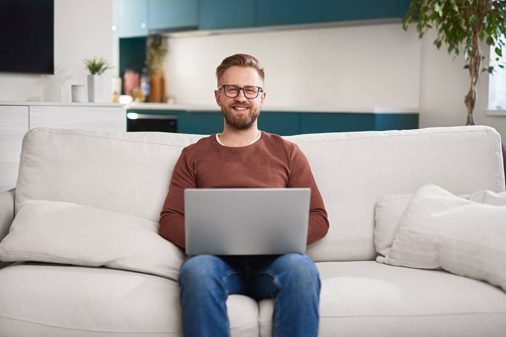 Hombre alegre usando el ordenador portátil en la sala de estar - Foto, Imagen