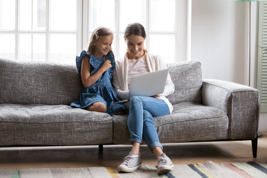 Mosolygó anya és kislánya használja laptop otthon - Fotó, kép