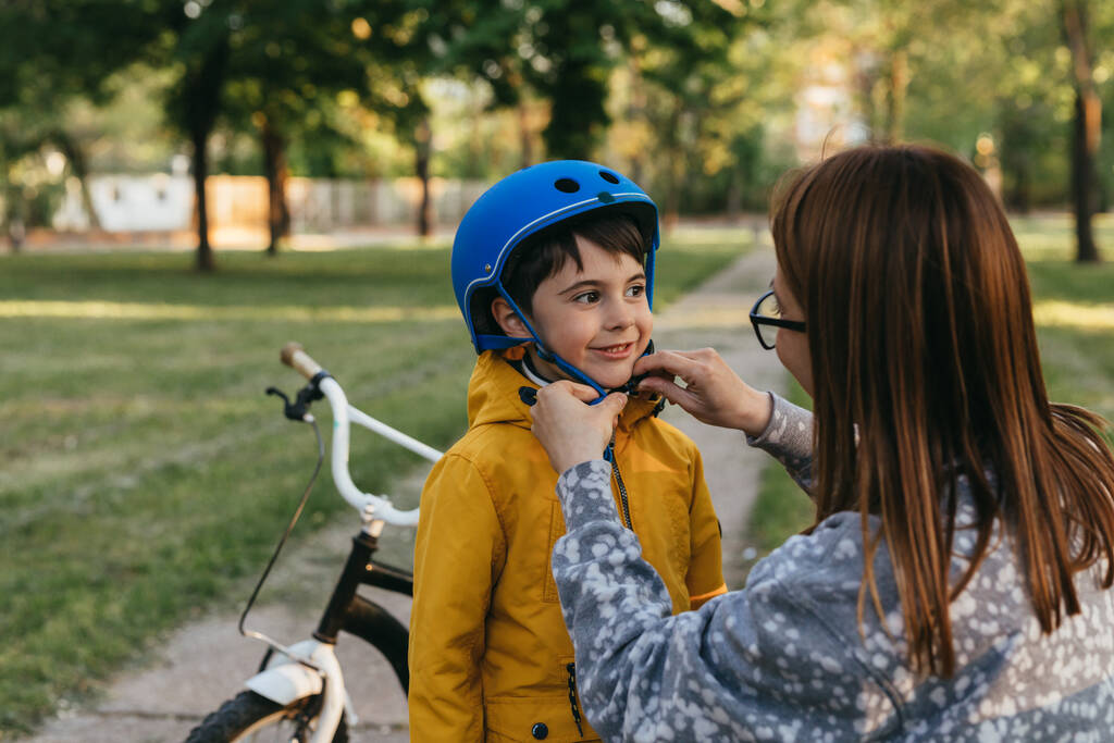 mère met un casque de vélo de sécurité sur la tête de ses fils - Photo, image