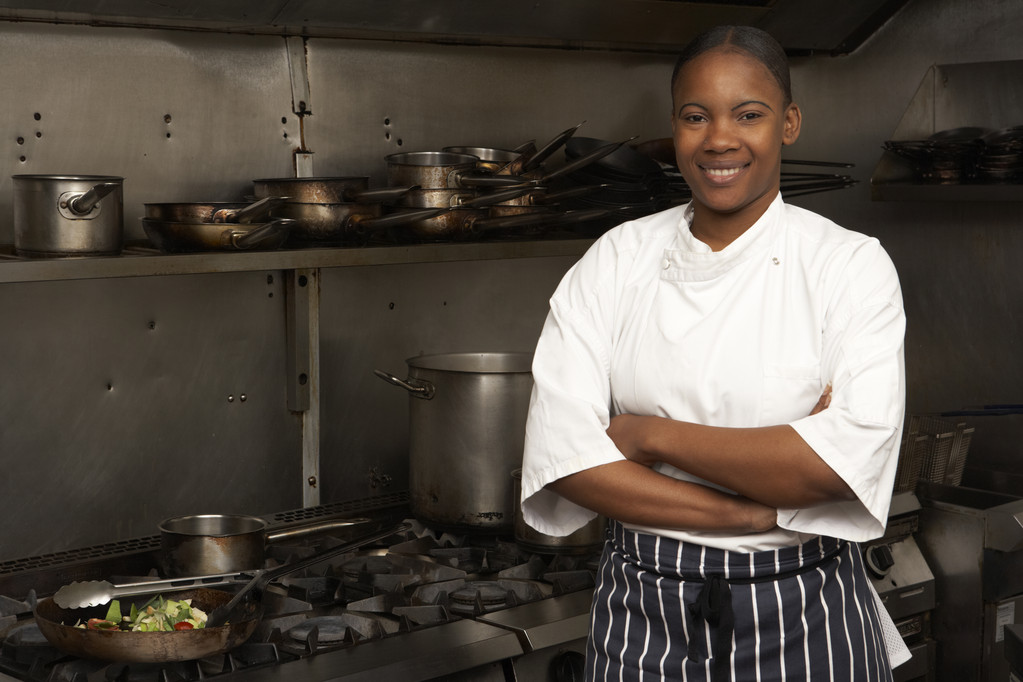 Chef femenino de pie junto a la cocina en la cocina del restaurante
 - Foto, Imagen