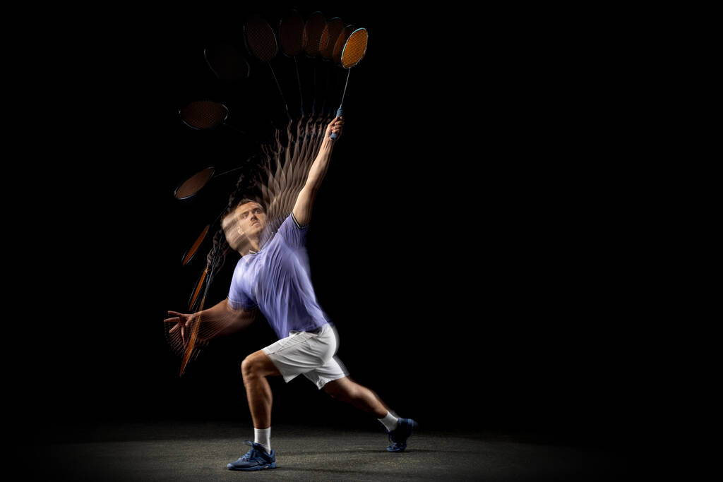 Portret van een jongeman, mannelijke badmintonspeler, shuttler die badminton speelt op donkere achtergrond. Stroboscoop-effect. - Foto, afbeelding