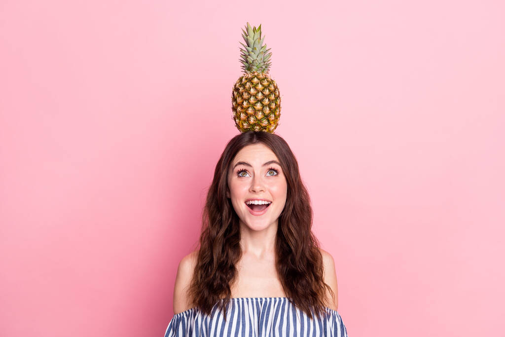 Fotografie šokované hezká mladá žena oblečená pruhované outfit drží hlavu ovoce hledá prázdný prostor izolované růžové barvy pozadí - Fotografie, Obrázek