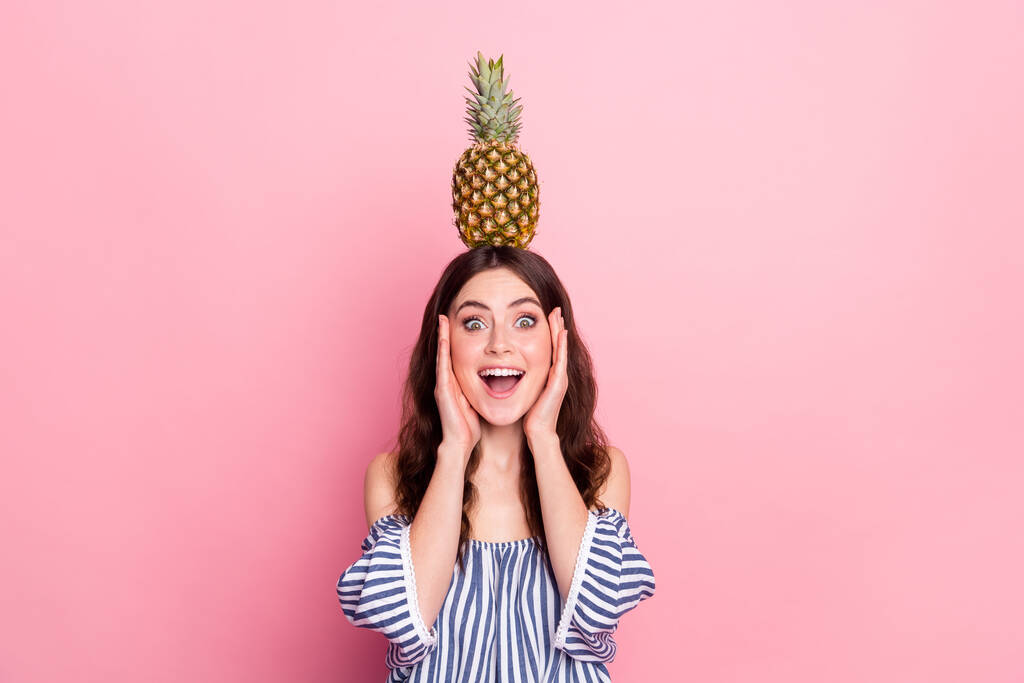 Foto van zoete onder de indruk jonge dame dragen off-schouders kleding houden hoofd ananas armen wangen geïsoleerde roze kleur achtergrond - Foto, afbeelding