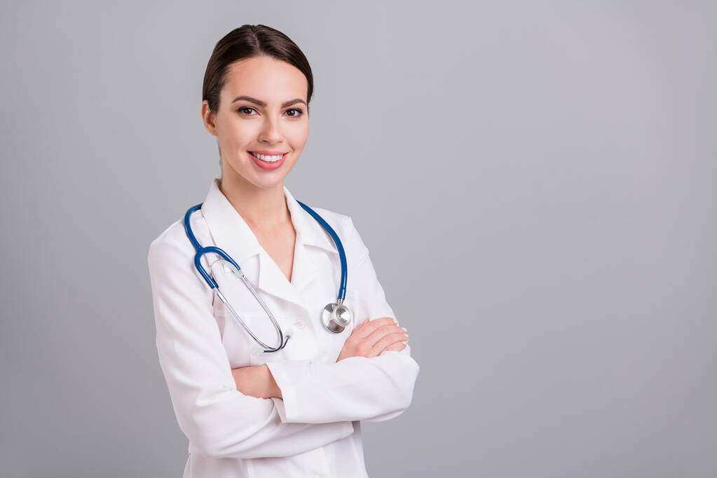 Photo portrait female doctor with sthethoscope smiling crossed hands isolated grey color background copyspace - Photo, Image