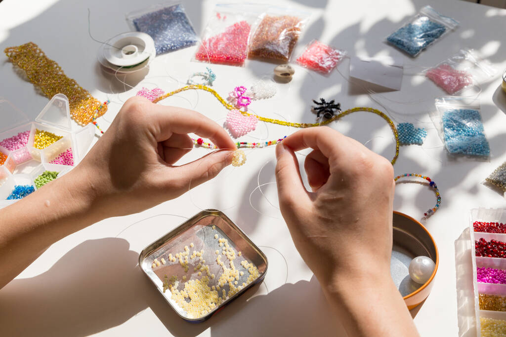 Beading workplace with hands in the process of handicraft. Beautiful diy jewelry and calming stress releasing hobby and activity - Photo, Image