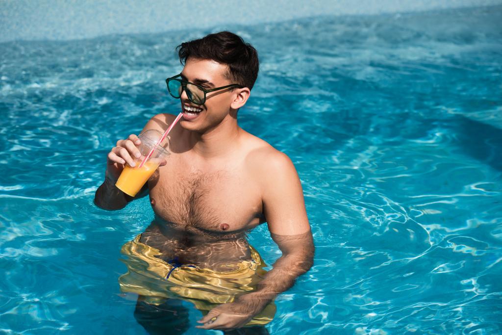 Nuori mies rentouttava appelsiinimehua uima-altaassa  - Valokuva, kuva
