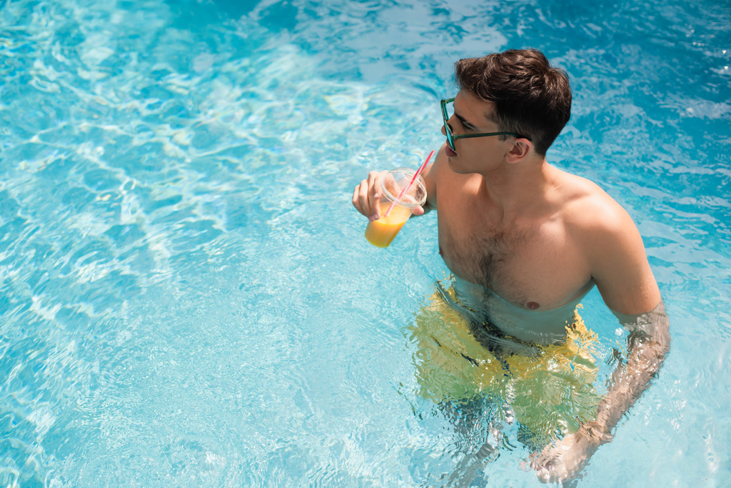 Nagy látószögű kilátás férfi gazdaság elvitelre ital a medencében  - Fotó, kép